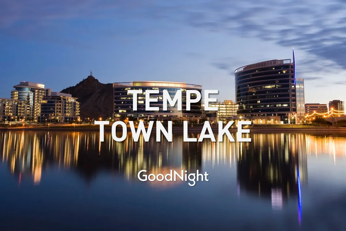 A tranquil waterfront scene featuring Tempe Town Lake, modern buildings, and a mountain backdrop. The scene is peaceful and picturesque, ideal for a sunset stroll, a relaxing break after meetings, or casual outdoor catch-ups. The view highlights the natural beauty accessible from the property.