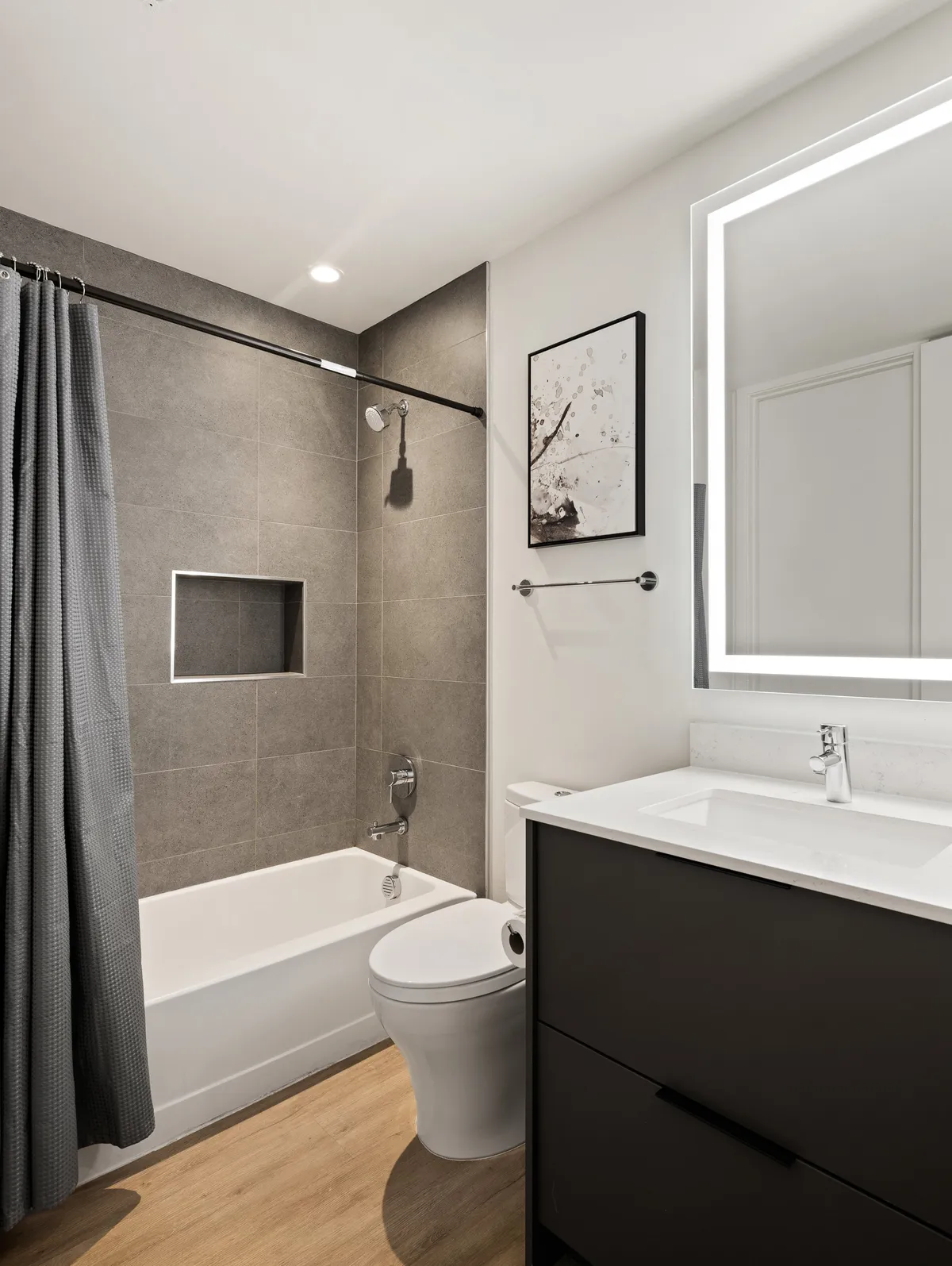 A tranquil bathroom scene showing a combination shower/tub, a vanity with sink, framed artwork, and plenty of space for self-care routines. The mood is fresh, soothing, and ideal for unwinding after a busy day.