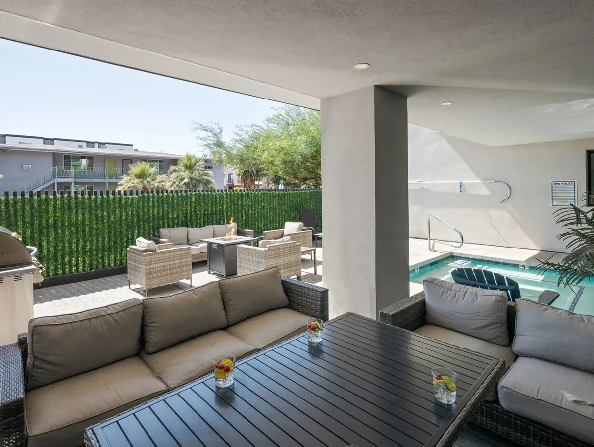 A serene outdoor pool area features inviting seating, lush greenery, and a table with drinks, suggesting relaxation and socializing after a day of adventure. The setting is casual, comfortable, and ideal for families or groups to gather.