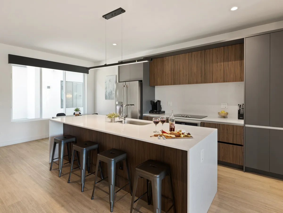 A welcoming kitchen and dining area featuring a central island with bar stools, high-end appliances, and a well-set dining table ready for meals or celebrations.