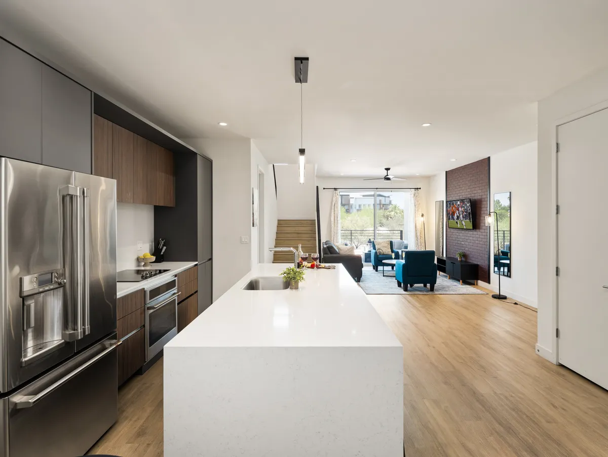 A contemporary open-concept interior showcases a spacious kitchen island with modern appliances, seamlessly flowing into a comfortable living area with ample seating and large windows that bring in natural light.